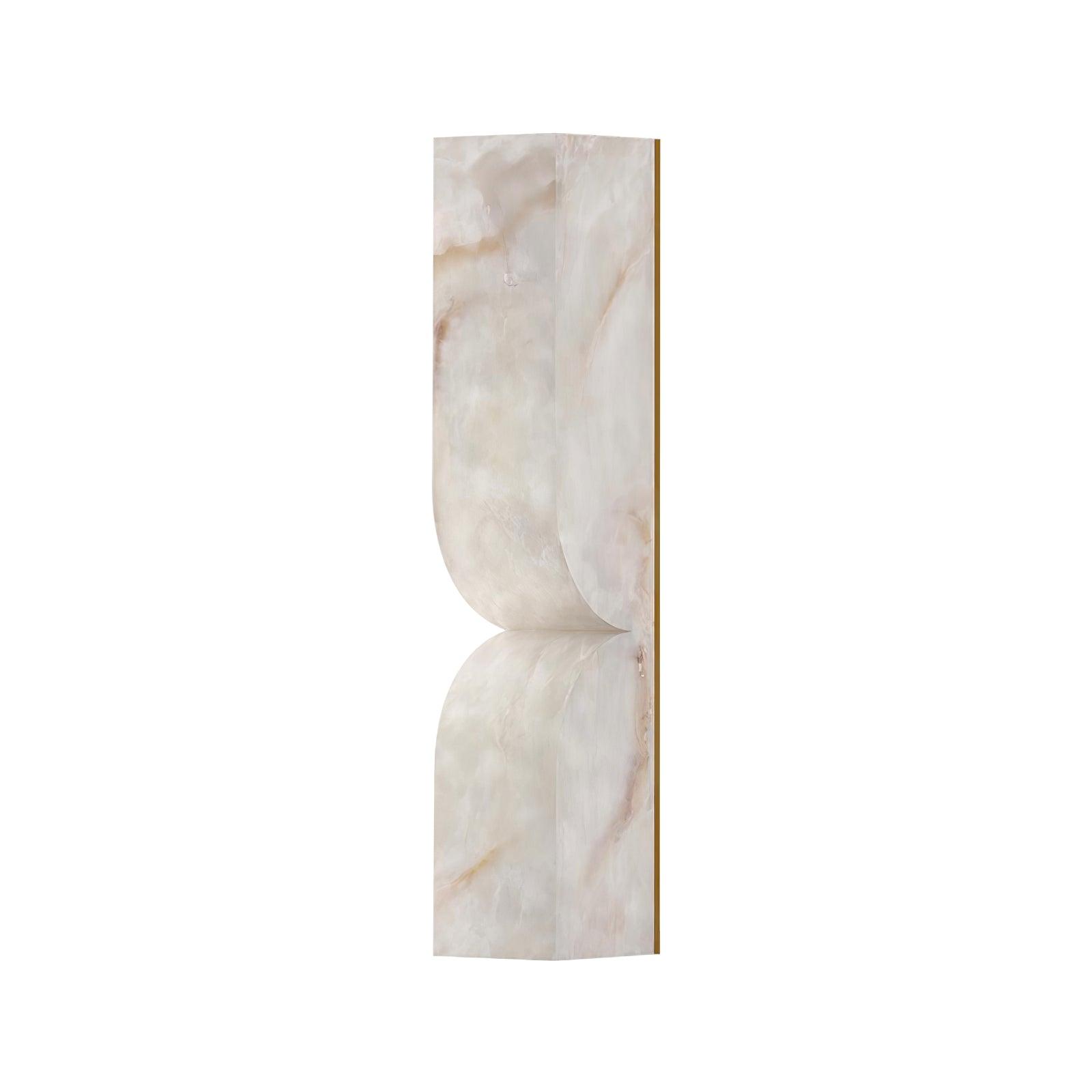 Carved alabaster wall light with warm sculptural glow on the wall