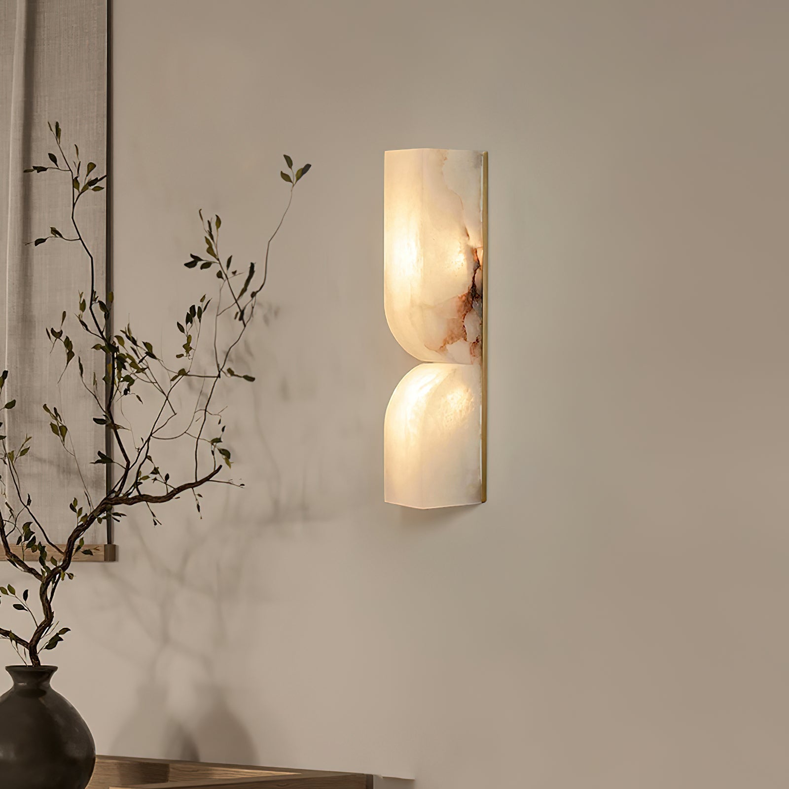 White carved alabaster wall light glowing warmly on an interior wall