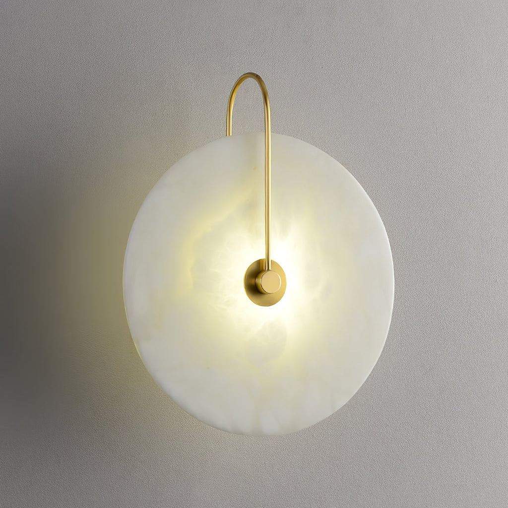 Gold-arm Elaris wall light lit on a grey wall, the tall arch of the arm fully visible above the disc.