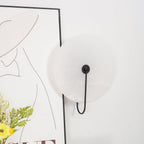 Close angled view of the unlit black Elaris wall light showing the matte surface of the stone disc.
