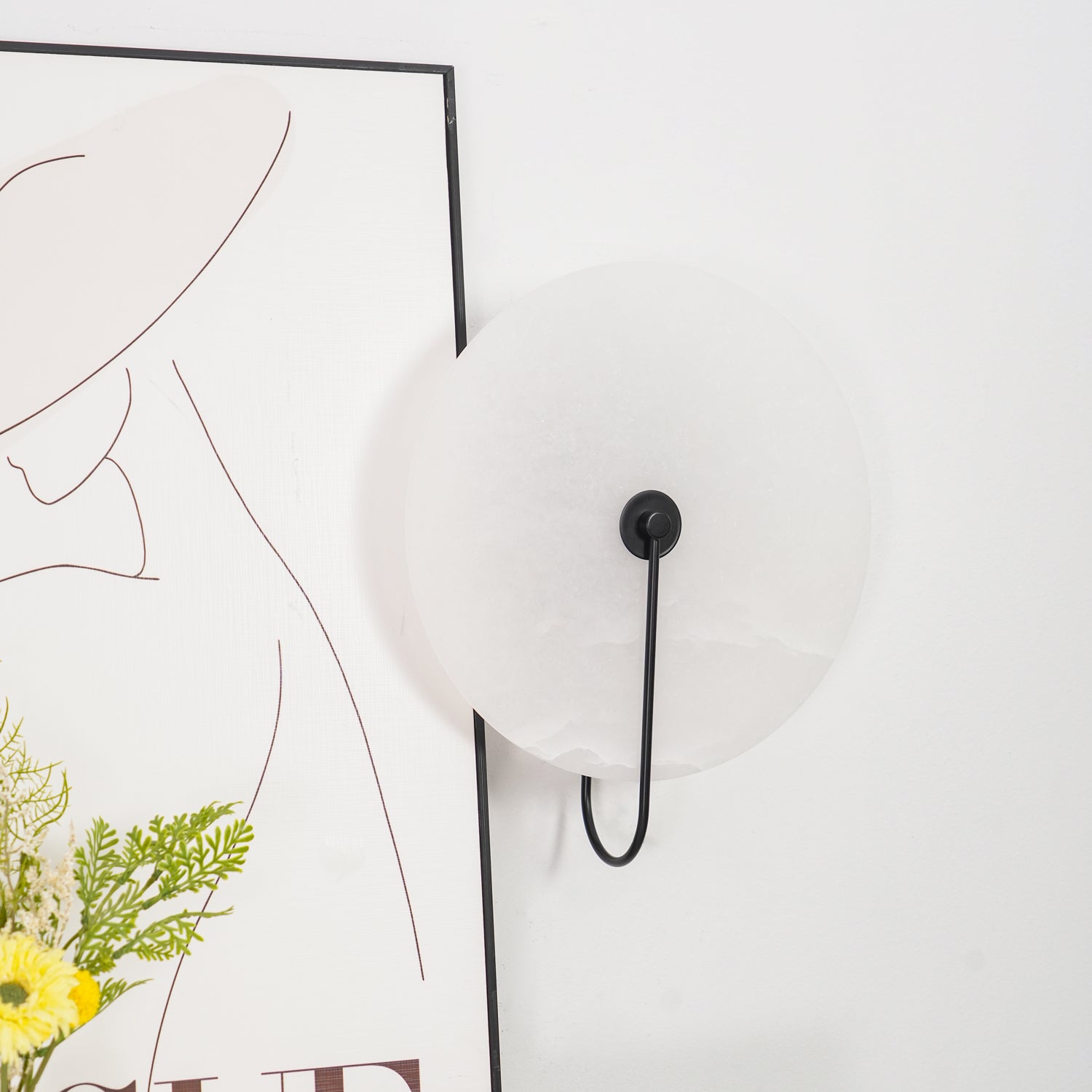 Close angled view of the unlit black Elaris wall light showing the matte surface of the stone disc.