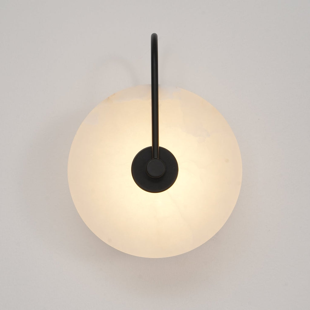 Straight-on view of the black Elaris wall light, the round mount disc sitting at the arm's end.
