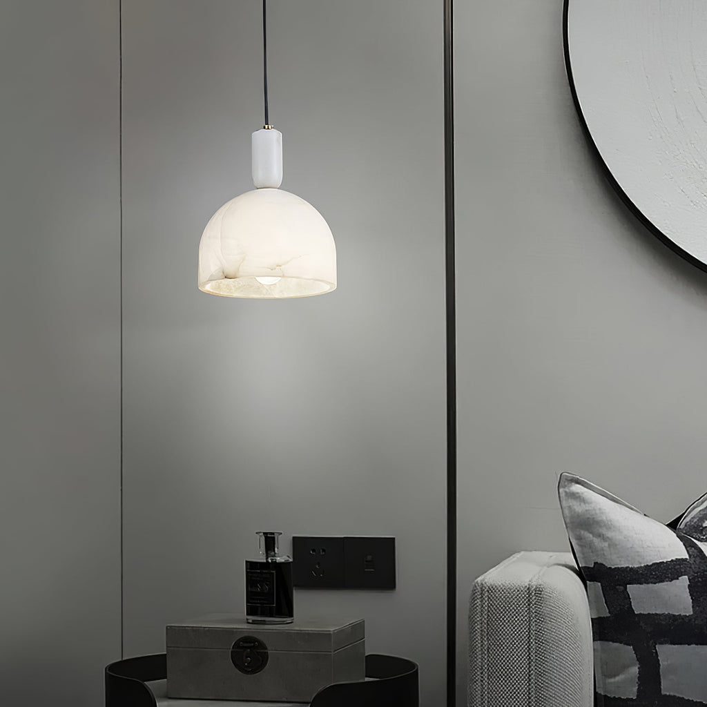 Clérachic alabaster pendant light glowing in a taupe-walled room, hanging near a round mirror and a perfume bottle on a box.
