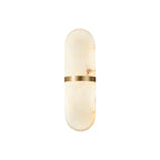 Clérachic ostruvyd alabaster wall lamp with brass band on a plain white background, softly lit from within