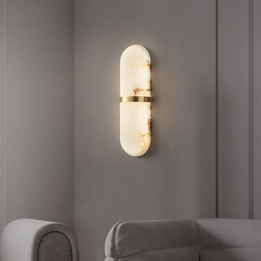 Clérachic brass-banded alabaster wall lamp lit above a grey sofa in a panelled sitting-room corner