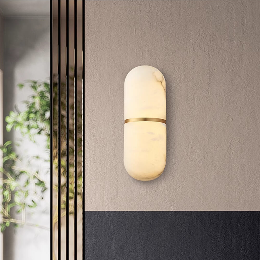 Clérachic alabaster wall lamp glowing on a textured beige plaster wall beside a slatted screen and greenery