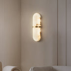 Clérachic angled view of the lit alabaster wall lamp, brass band and stone veining seen from the side