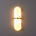 The Clérachic alabaster wall lamp lit head-on, brass band splitting the glow into upward and downward halves