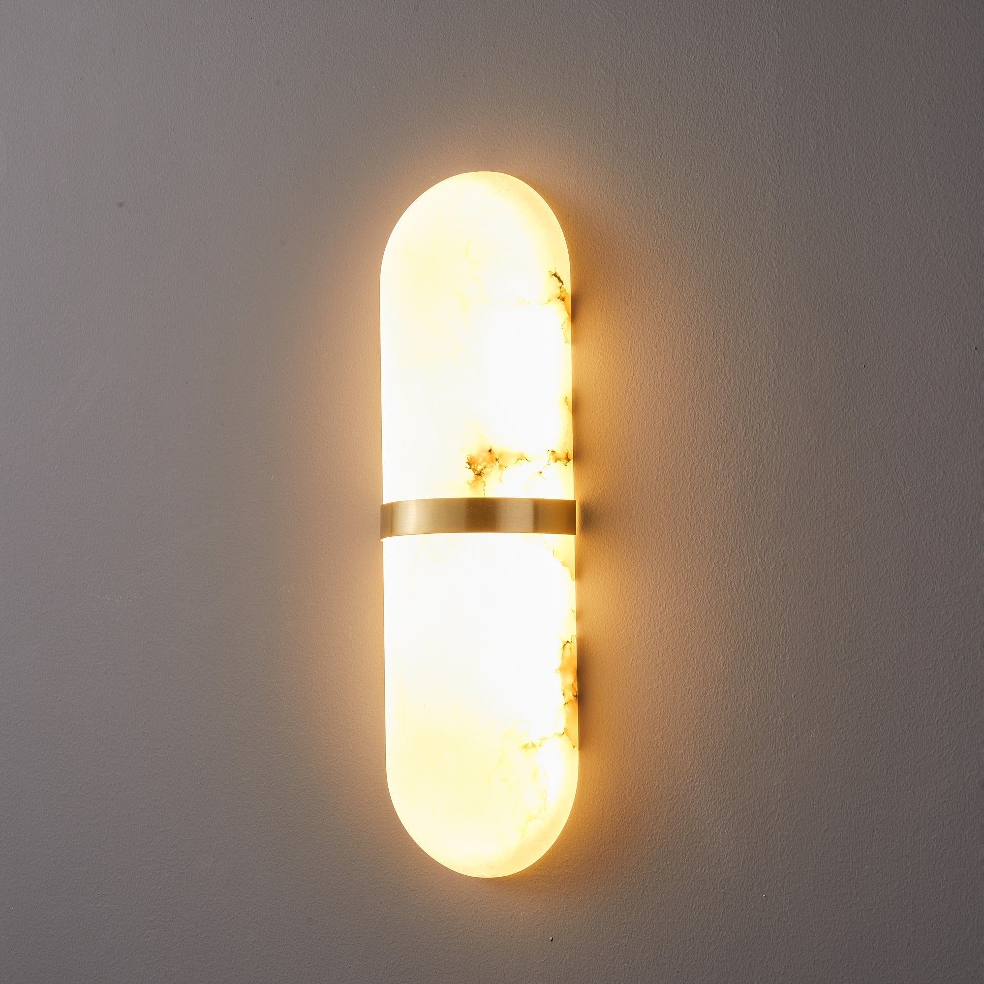 Clérachic side-angle view of the lit lamp, showing how the alabaster shade stands off the wall