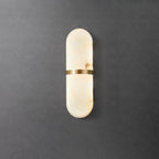 Clérachic brass-banded alabaster wall lamp on a dark concrete wall, warm amber veins visible in the stone