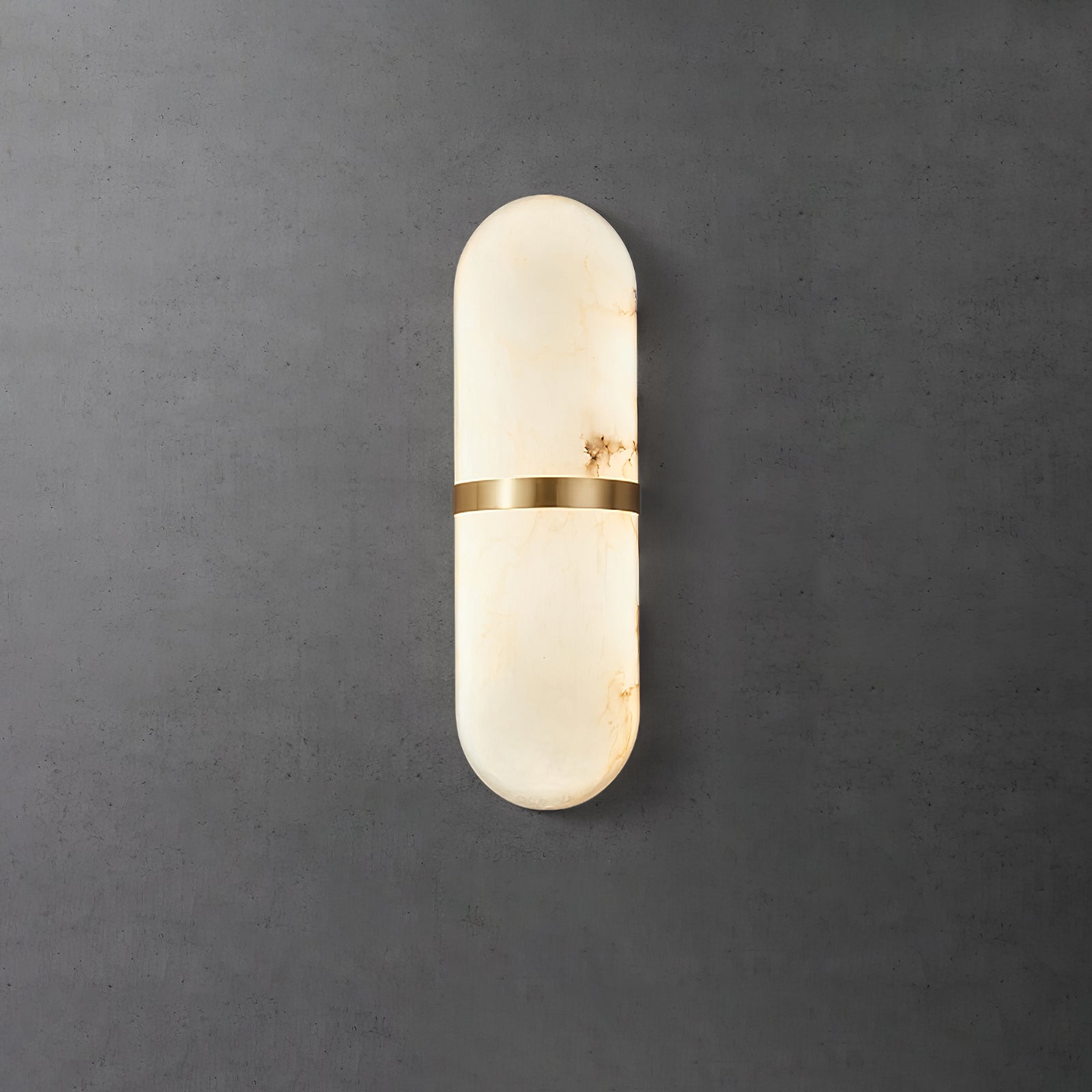 Clérachic brass-banded alabaster wall lamp on a dark concrete wall, warm amber veins visible in the stone
