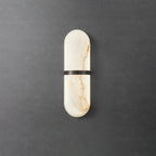 Clérachic slim alabaster wall lamp with a dark bronze band, softly lit on a textured concrete wall