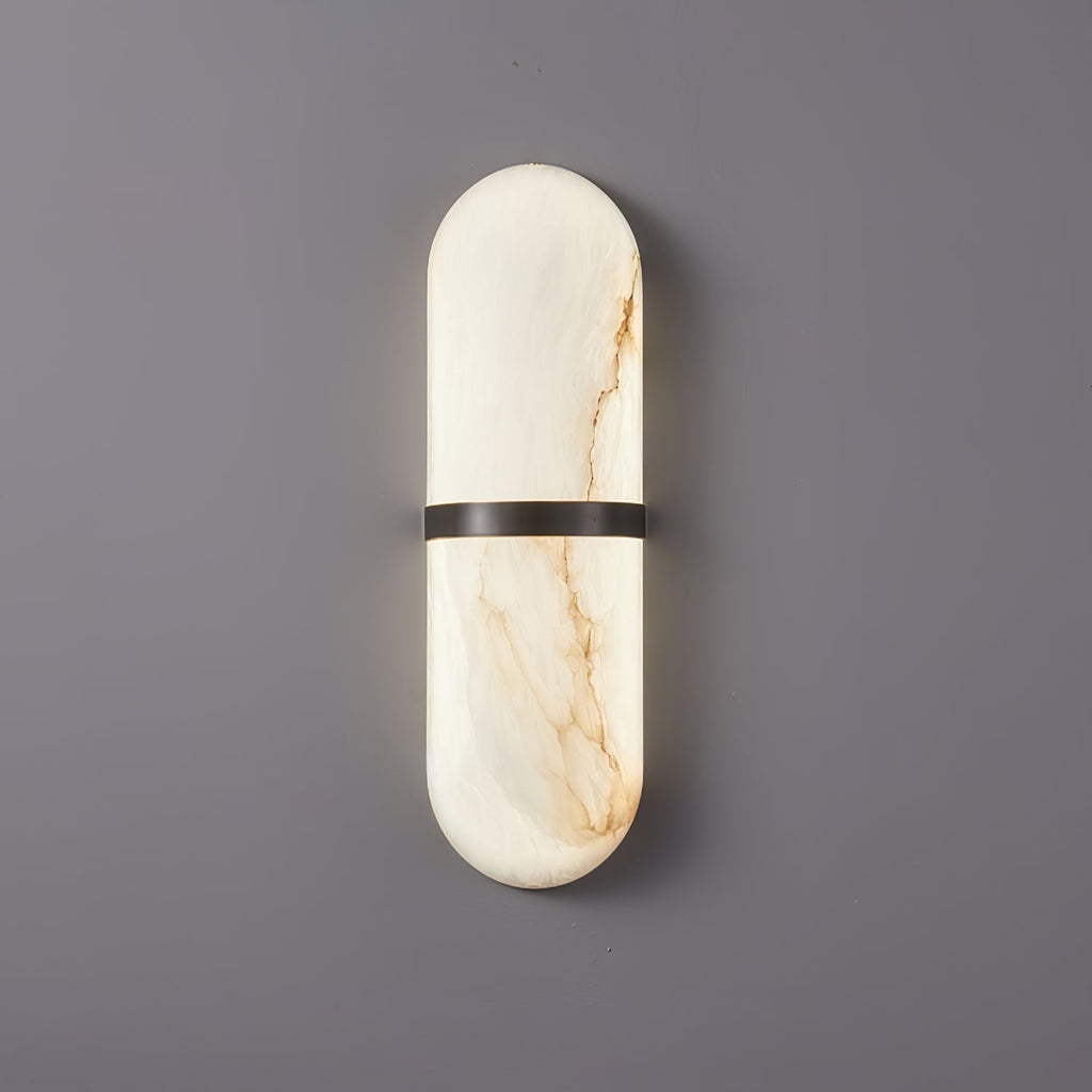 Clérachic wide alabaster wall lamp with bronze band, lit low, a honey vein running the length of the shade