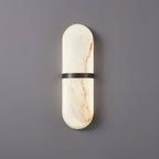 Clérachic wide alabaster wall lamp with bronze band, lit low, a honey vein running the length of the shade