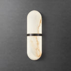 Clérachic bronze-banded alabaster wall lamp glowing softly against a dark textured concrete wall