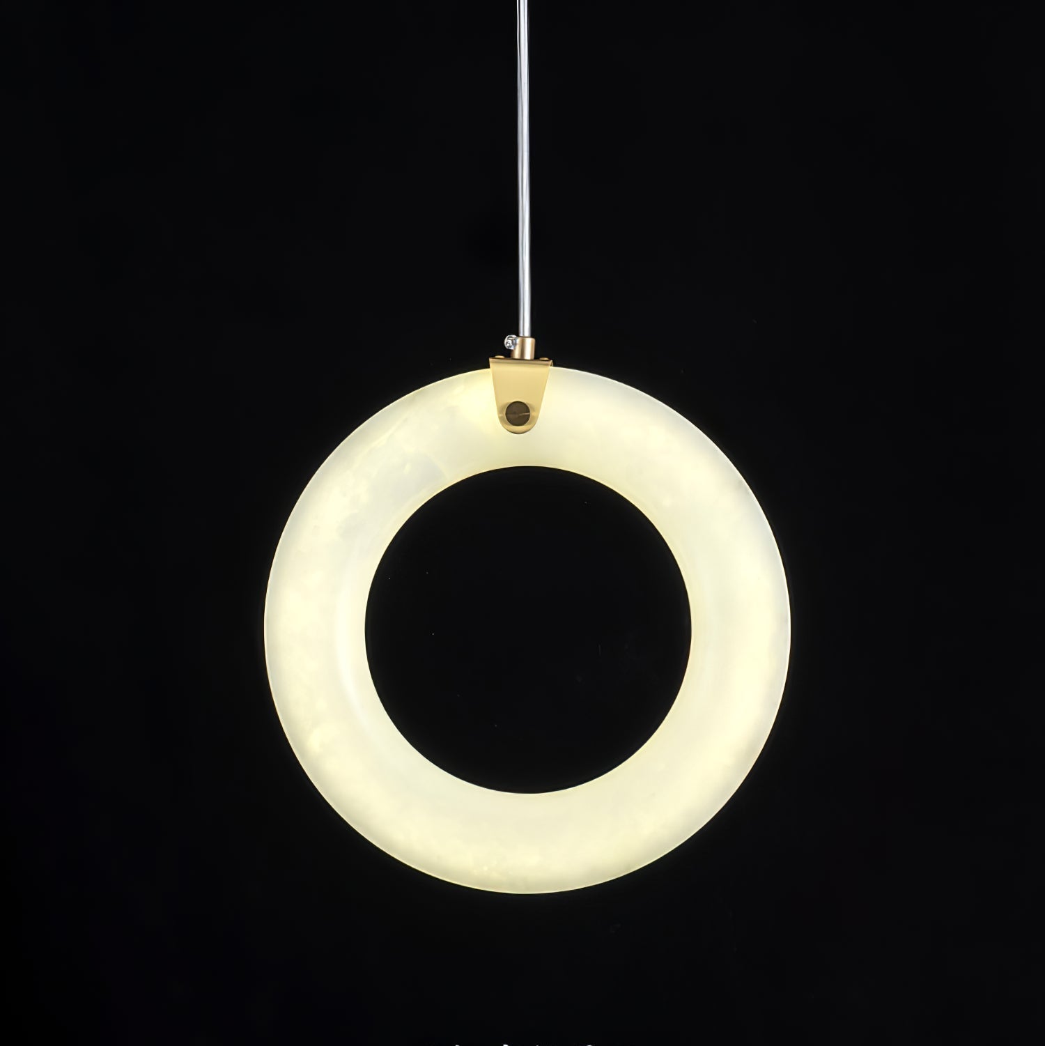 Alabaster ring pendant switched on against black, face-on, warm light spread evenly around the ring