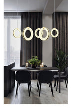 Tall view of the five-pendant row over a black dining table with chairs and pale wood floor