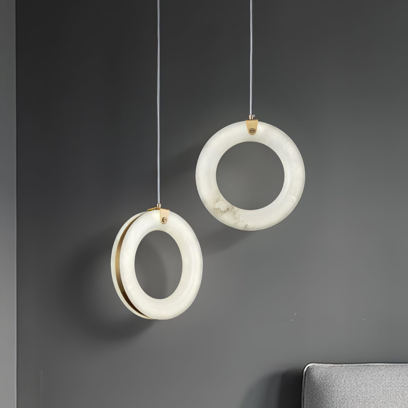Two unlit alabaster rings showing the natural stone veining and the slim brass band behind