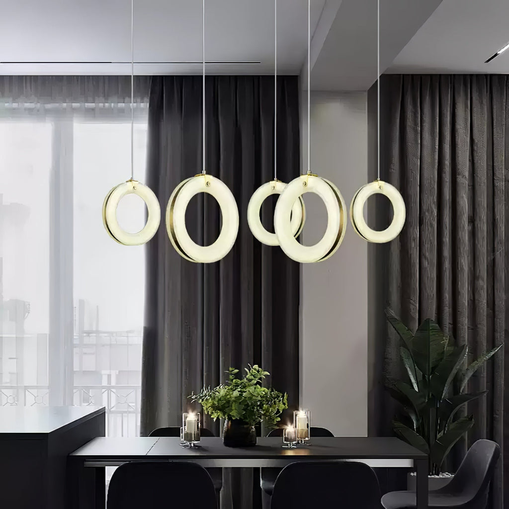 Five alabaster ring pendants in a row above a dark dining table, glowing against charcoal curtains