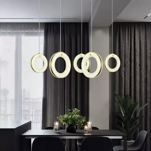 Five alabaster ring pendants in a row above a dark dining table, glowing against charcoal curtains