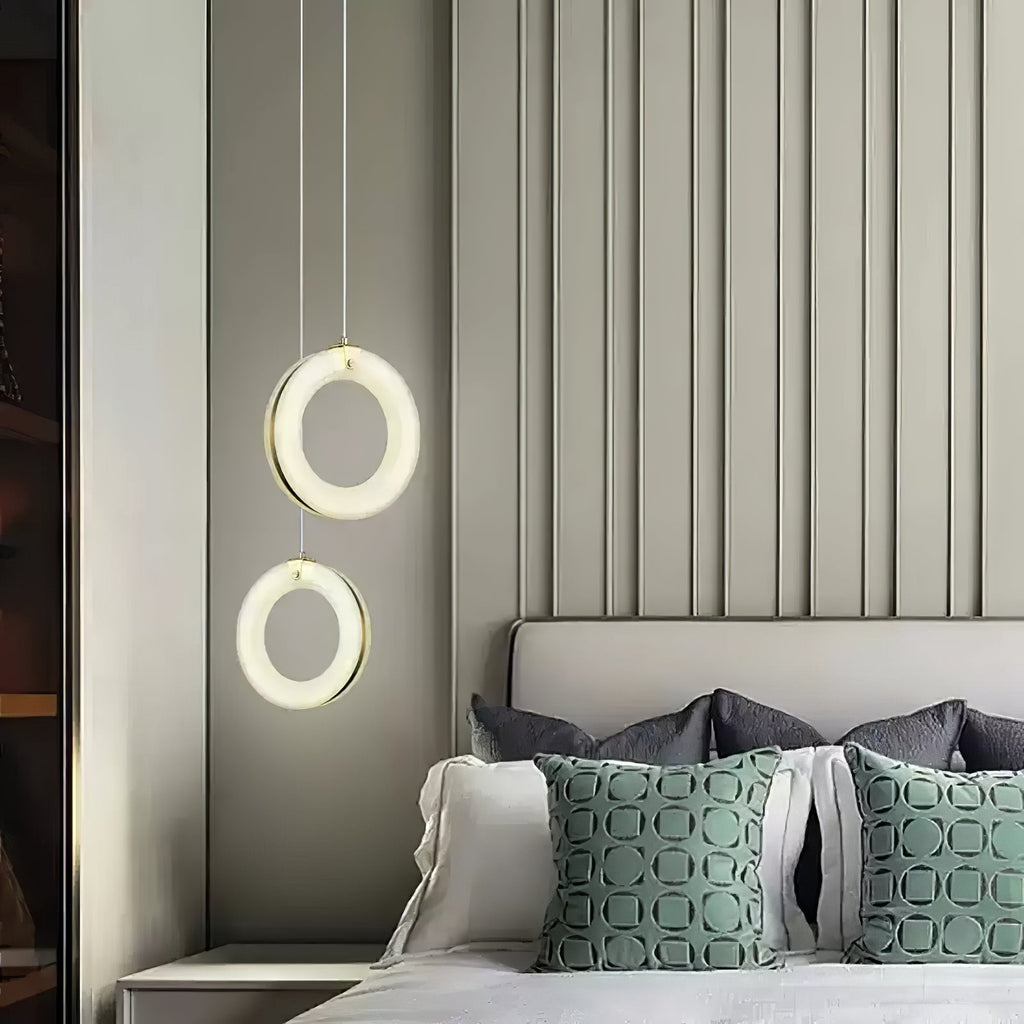 Pair of alabaster ring pendants hung one above the other next to a headboard and green cushions