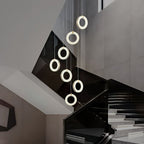 Seven alabaster ring pendants cascading down a stairwell above a black glass balustrade
