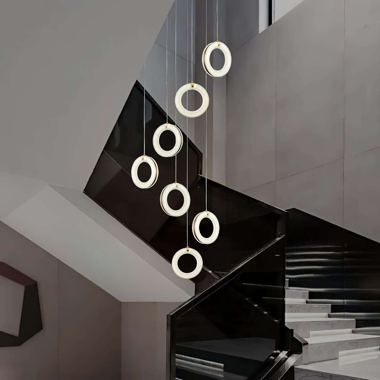 Seven alabaster ring pendants cascading down a stairwell above a black glass balustrade