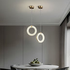 Two alabaster ring pendants on brass ceiling canopies above a round marble dining table