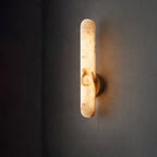 The sconce lit against a dark grey wall, warm light spilling from both ends of the bar.