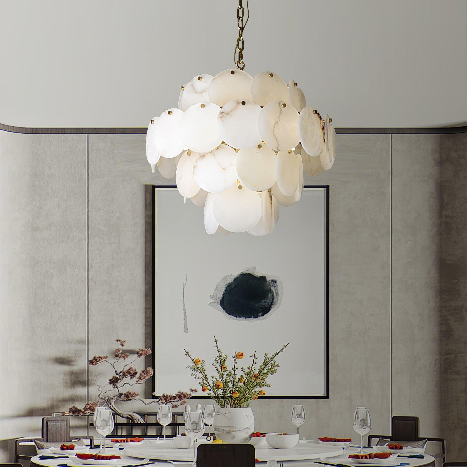 The chandelier lit above a laid dining table in a grey room with a large framed print.