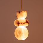 Close-up of the lit alabaster pendant against a warm terracotta wall, light glowing through the stone