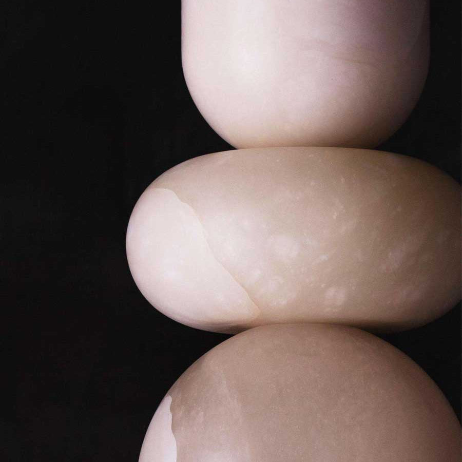 Macro crop of the pendant's cream alabaster forms against black, showing the seams where sections meet
