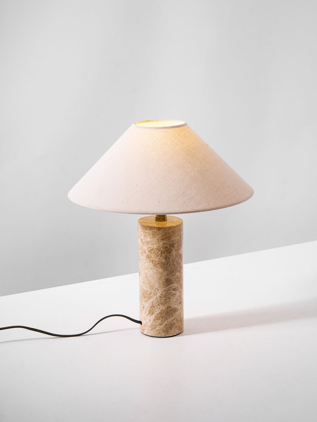 The Clérachic table lamp on a plain studio background, its cord trailing across the floor beside the marble base.