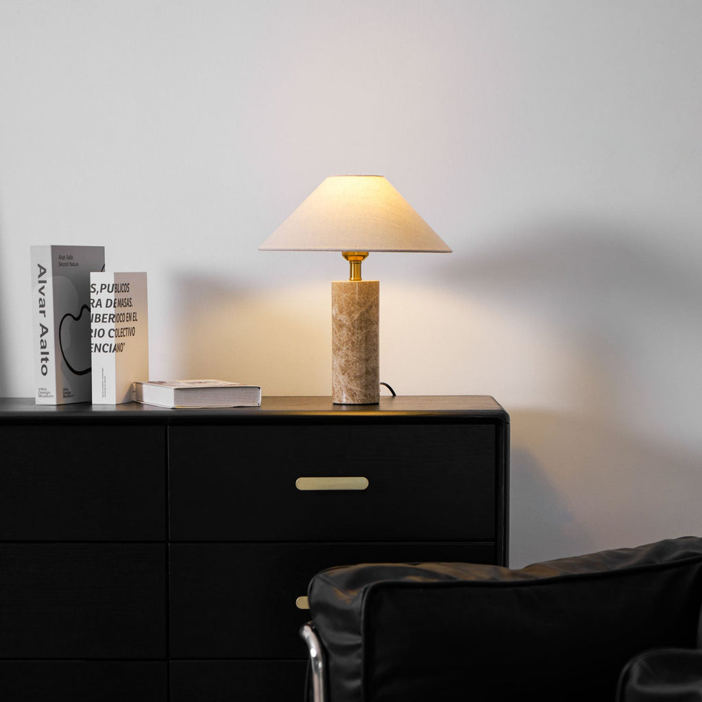The Clérachic table lamp glows on the dresser, books stacked to its left and the chair's edge visible at the bottom.