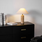 Full brightness view of the Clérachic table lamp on the dresser, books leaning together and the chair fully in frame.