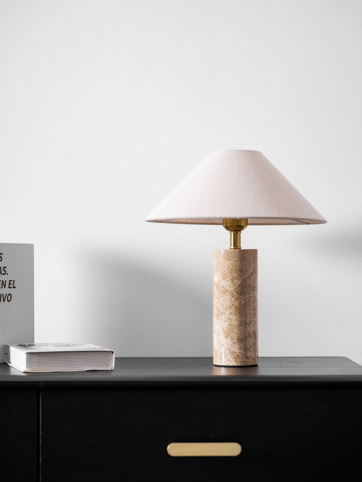 A narrow crop of the dresser corner shows just the Clérachic table lamp, a flat book and the drawer pull below.