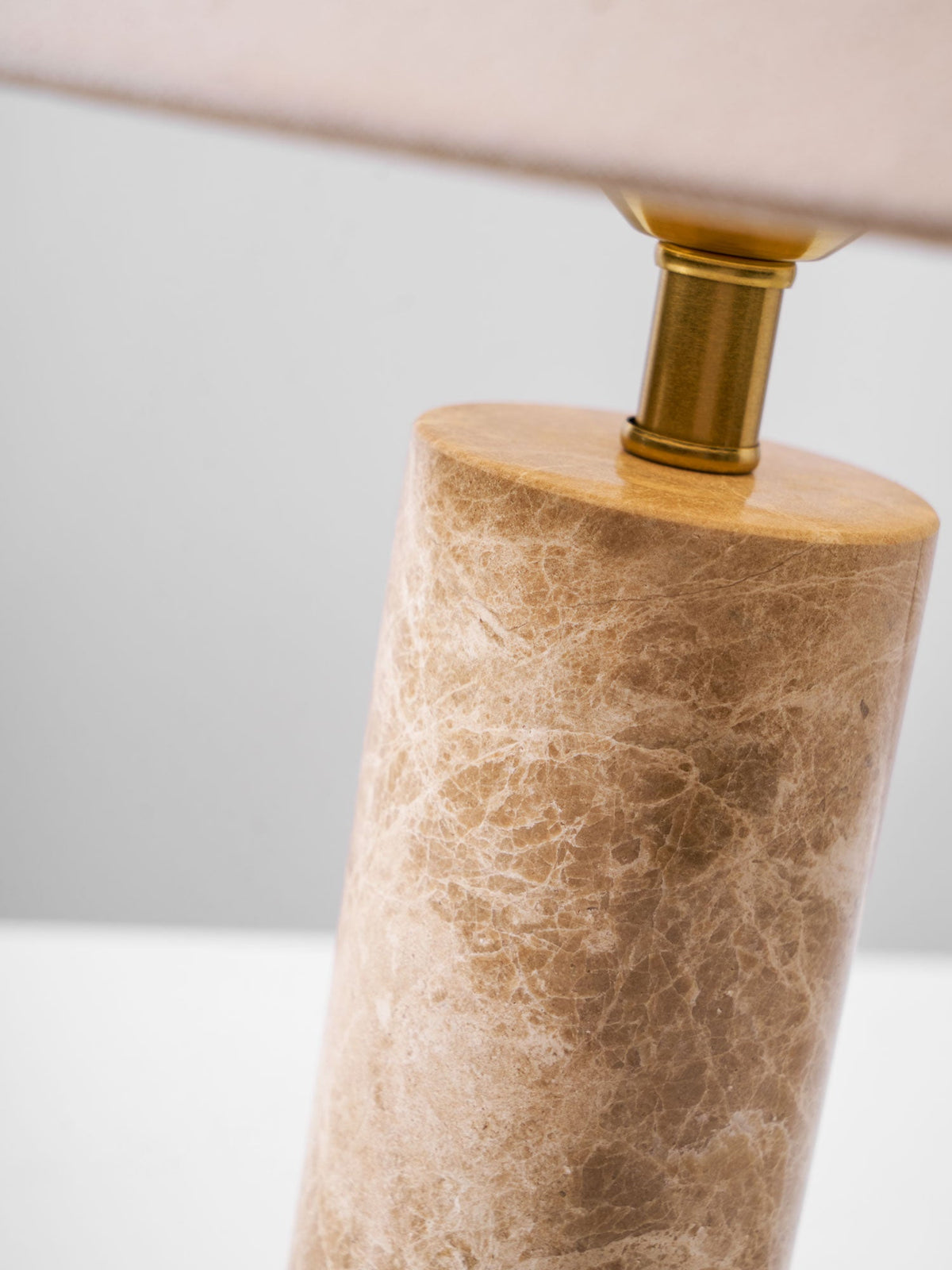 Macro detail of the brass neck joining the Clérachic table lamp's shade to its marble column.