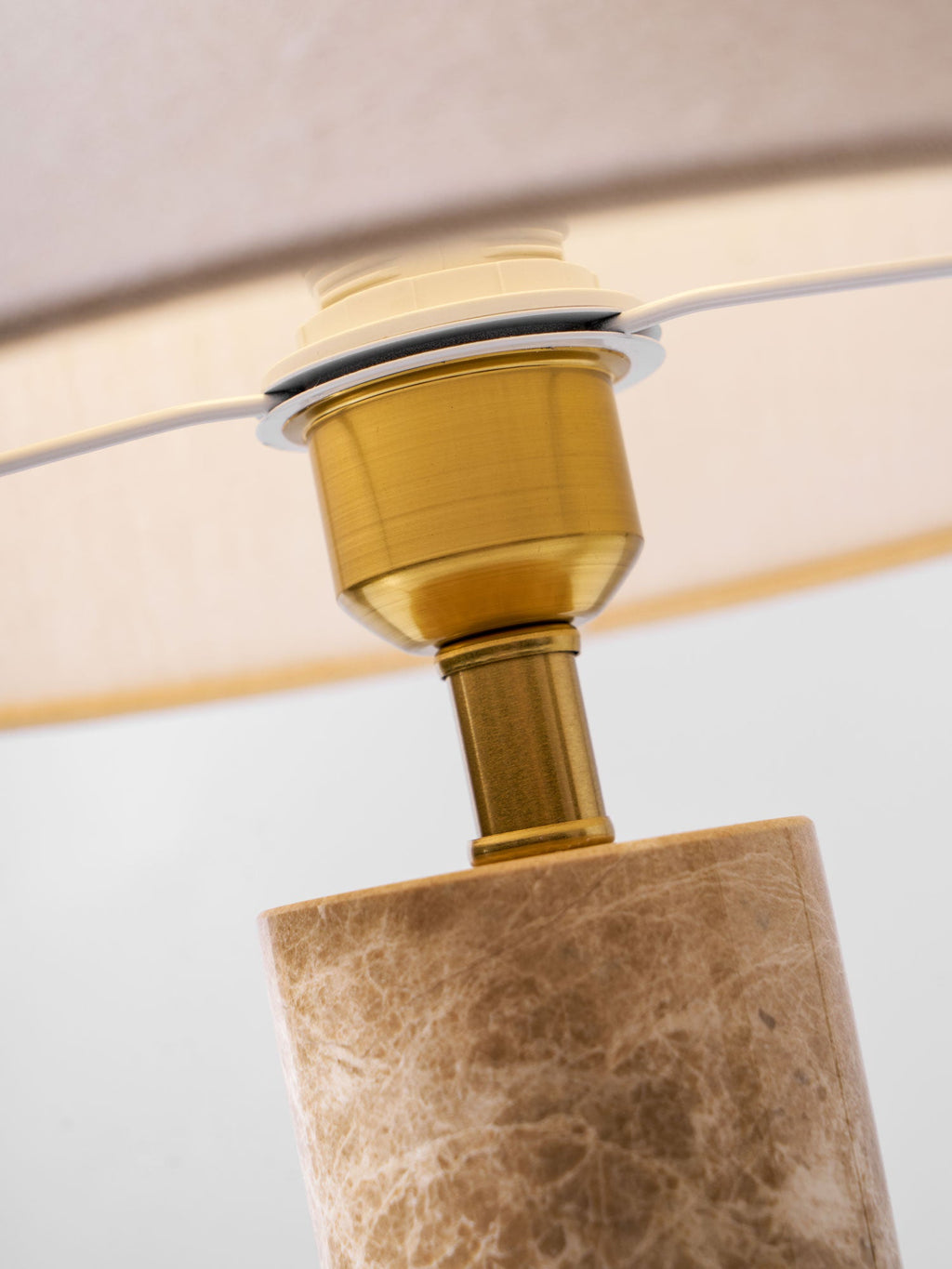 Macro detail of the brass socket and bulb fitting where the Clérachic table lamp's shade meets the marble base.