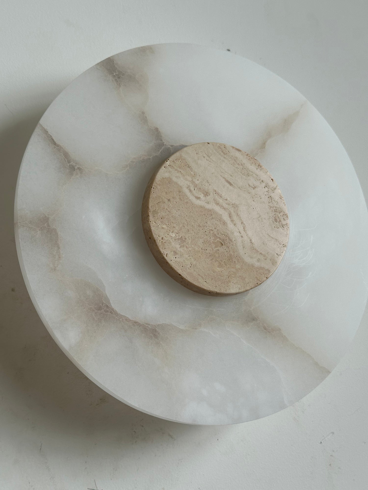 Clérachic close-up of the Rauduvyi wall lamp showing the travertine disc and the brown veining in the alabaster