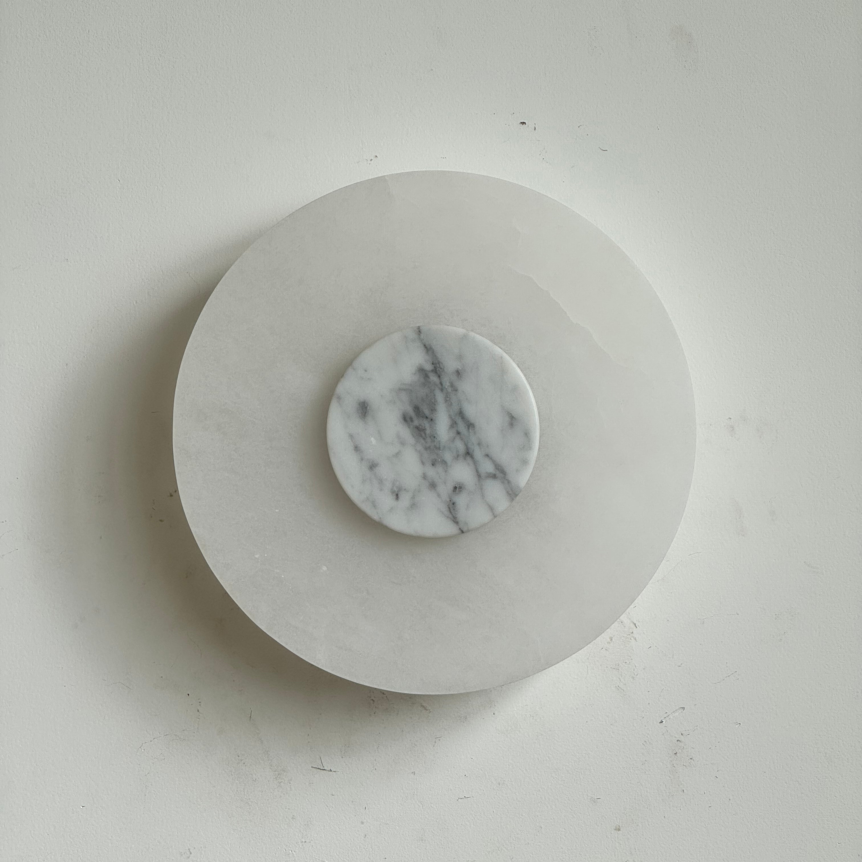 Clérachic rauduvyi alabaster wall lamp seen straight on, unlit, with a grey-veined white marble centre disc