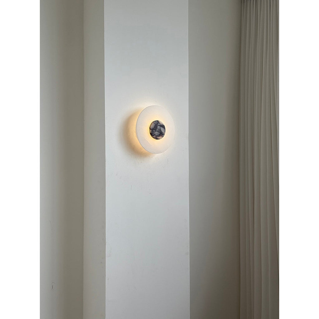 Clérachic rauduvyi wall lamp lit on a narrow wall pier beside floor-length pleated curtains