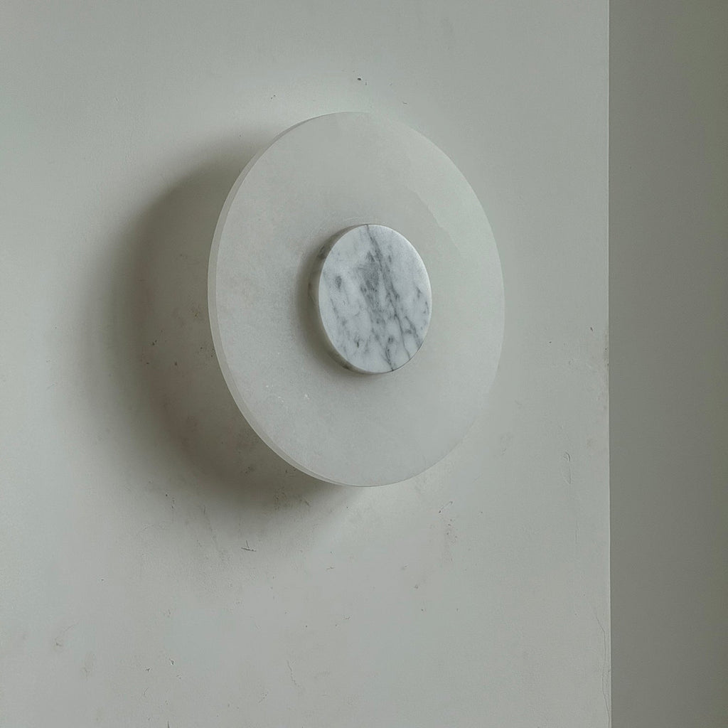 Clérachic rauduvyi wall lamp unlit at a three-quarter angle, white grey-veined marble disc at its centre