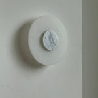 Clérachic rauduvyi wall lamp unlit at a three-quarter angle, white grey-veined marble disc at its centre