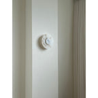 Clérachic rauduvyi wall lamp switched off on a pale wall pier next to a pleated floor-length curtain