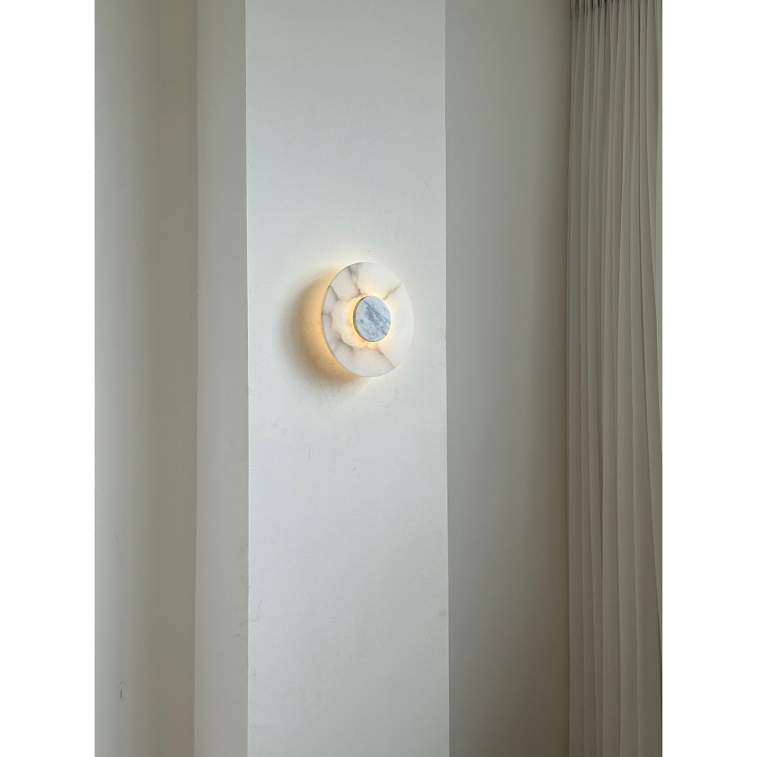 Clérachic lit Rauduvyi wall lamp on an interior wall, its glow reflecting softly onto the plaster around it