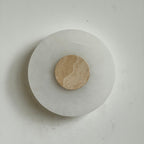 Clérachic rauduvyi alabaster wall lamp with a warm beige travertine centre disc, unlit against a pale wall