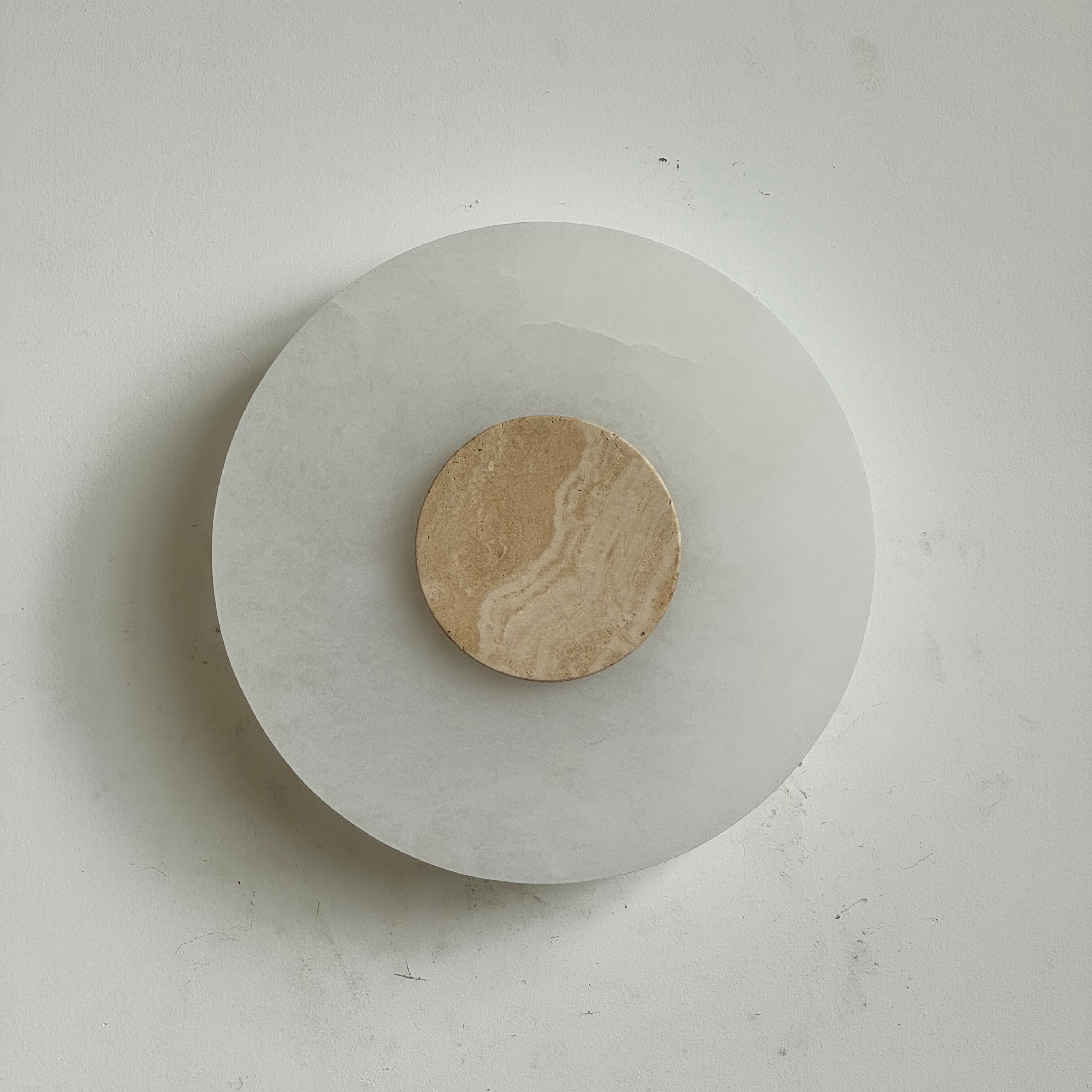 Clérachic rauduvyi alabaster wall lamp with a warm beige travertine centre disc, unlit against a pale wall