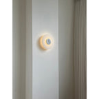 Clérachic rauduvyi wall lamp glowing on a plain interior wall, seen from across the room at eye level