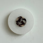 The Clérachic Rauduvyi wall lamp unlit, its violet-veined marble disc contrasting with the milky alabaster plate