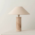 The Clérachic table lamp stands on a raised plinth against a plain background, its ivory shade lit warmly.